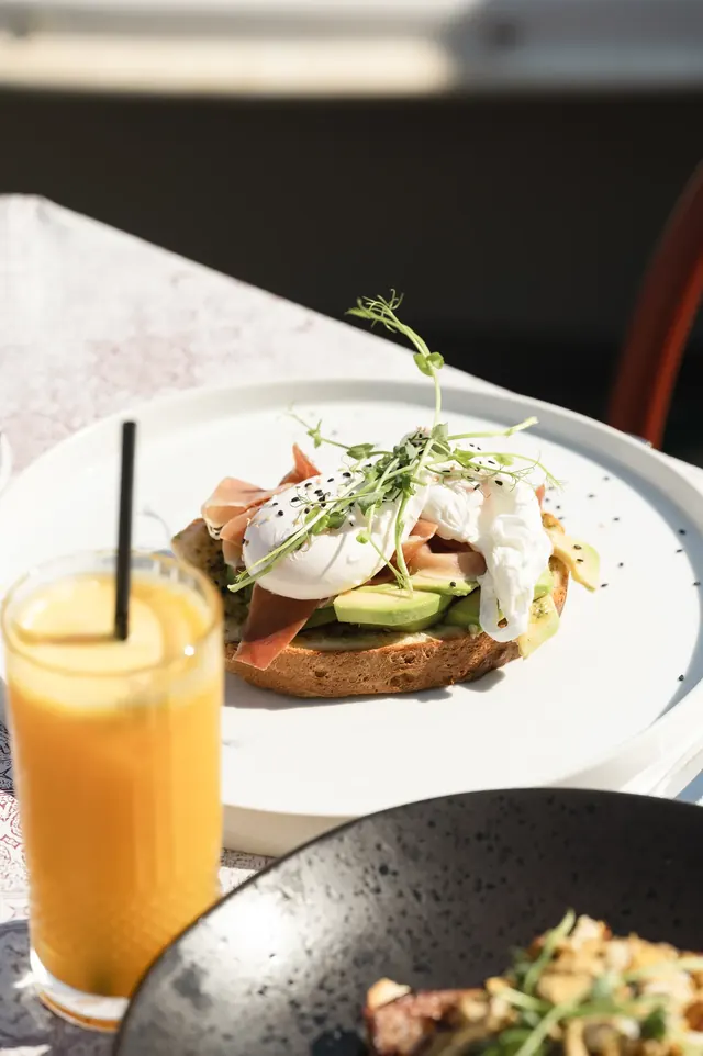 Poached eggs, avocado and ham with fresh orange juice